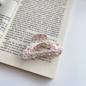 Details einer Haarklammer aus Acetat mit rosa Blumenmuster auf einem Vintage-Buch