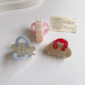 Three acetate hair claws with checkered and gradient patterns on a white background