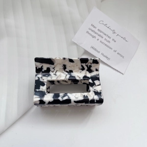 Detail of a rectangular acetate hair claw clip with black and white marble pattern texture