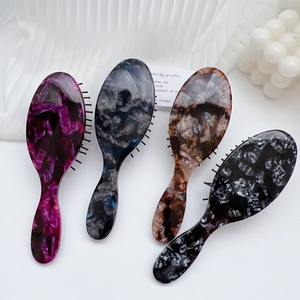 Detail view of acetate massage hair combs with elegant marble patterns in four colors