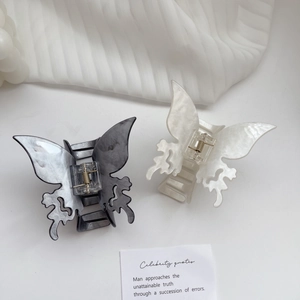 Elegant butterfly hair claw clips in marble and pearl textures on a white fabric background