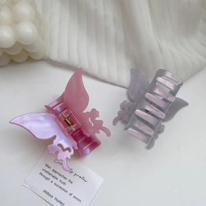Elegant butterfly hair claw clips in gradient pink and purple on soft white fabric