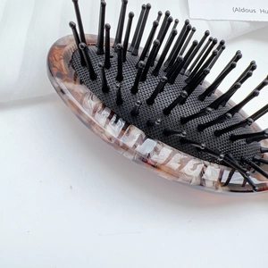 Detail shot of a tortoiseshell acetate cushion hairbrush with black massage bristles