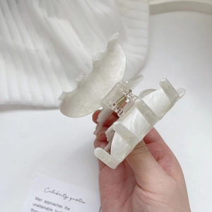 Detailed view of a white butterfly hair claw clip with a pearlescent finish and gold spring