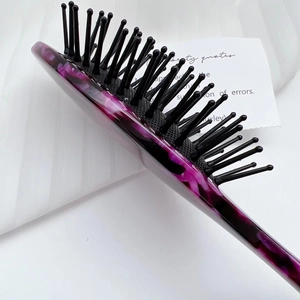 Macro detail of purple marble acetate hairbrush with flexible air cushion and nylon pins
