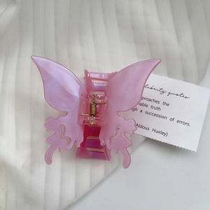 Macro detail of a pearlescent pink butterfly hair claw clip with a gold metal spring