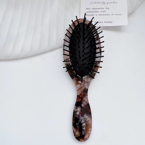 Detailed macro view of the marble texture and massage bristles on the acetate hairbrush