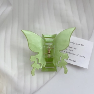Detail of light green butterfly hair claw clip with pearlescent finish and hollow design