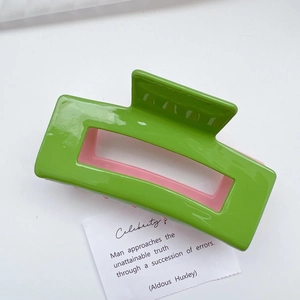 Detail of a large square cutout hair claw clip in vibrant green and pink contrast colors