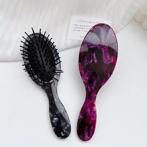 Marble textured anti-static cushion hairbrush with ergonomic handle on minimalist background