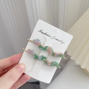 Detail view of wavy acetate hair clips with marble texture and France Handmade logo