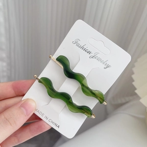 Pair of vintage green wavy acetate hair clips on a white fashion jewelry display card