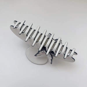 Detail view of a large white acetate hair claw clip with black butterfly outline
