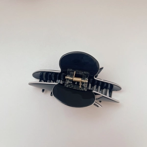 Detail of black and white acetate butterfly hair claw with golden metal spring