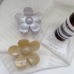 Elegant acetate flower hair claw clips with pearlescent finish on white fabric