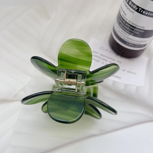 Detailed close-up of dark green marble floral hair claw clip with golden metal spring