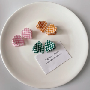 French heart-shaped checkered hair claws in pink, orange, and green on a white plate