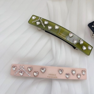 Detailed macro view of pink and green acetate hair clips with heart rhinestones