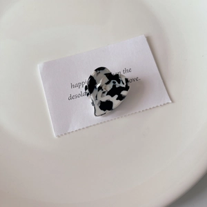 Close-up of heart-shaped hair claw clip with black and white marble pattern on white plate