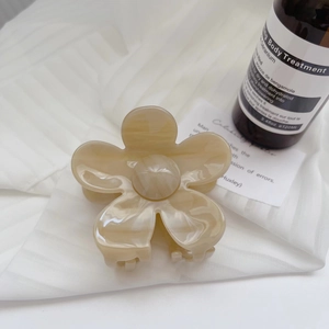 Macro detail of elegant cream flower hair claw clip on soft pleated white fabric