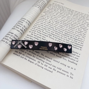 Detail of handmade acetate hair clip with pink crystal heart and rhinestones on book