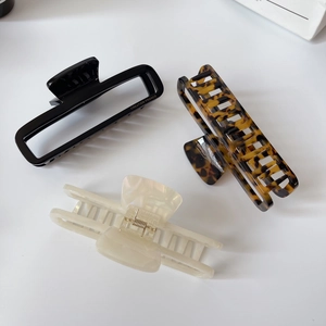 Detailed view of large square acetate hair claws in black, tortoiseshell, and pearl white