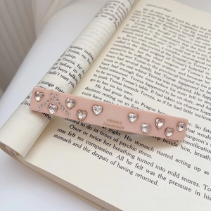 Close-up of handmade French style acetate heart rhinestone hair clip on vintage book