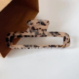Detail of rectangular tortoise shell hair claw with hollow design and leopard pattern print