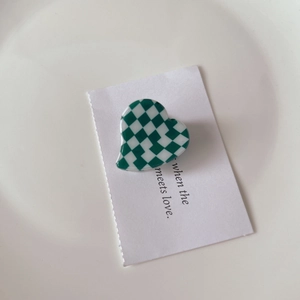 Detail of green and white checkerboard heart hair claw clip on aesthetic card