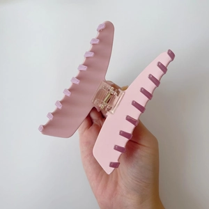 Gros plan détaillé d'une pince à cheveux mate rose avec un ressort translucide