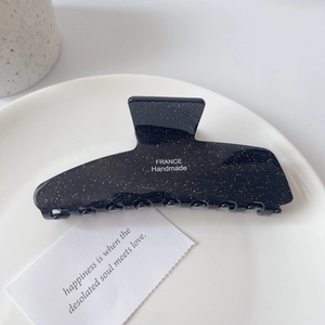 Détail de la pince à cheveux noire pailletée avec texte France Handmade sur plateau