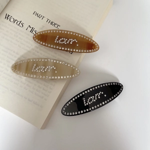 Detailed view of three acetate hair clips with inlaid rhinestones on a vintage book