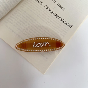 Close-up of tortoise shell resin hair clip with sparkling Love rhinestone lettering on a book