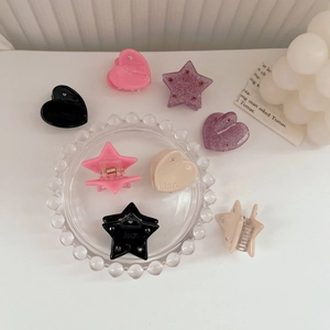 Dettaglio di mini mollette per capelli in acetato a forma di stella e cuore color pastello