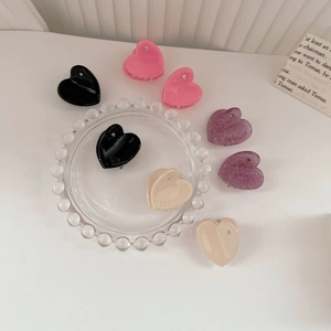 Dettaglio di mini mollette per capelli a forma di cuore in vari colori con piccoli strass