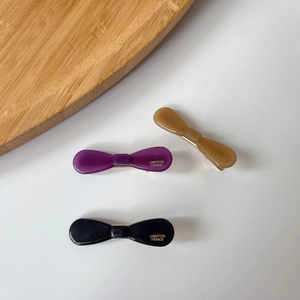Detailed macro view of acetate bow hair clips with elegant Creation France gold lettering