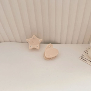 Dettaglio di mini mollette per capelli a cuore e stella con strass in acetato rosa