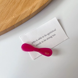 Close-up of magenta acetate bow hair clip featuring gold-stamped France engraving
