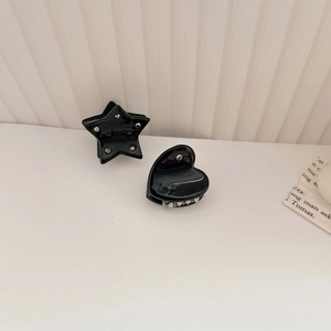 Dettaglio delle mini mollette per capelli in acetato nero con strass a stella e cuore
