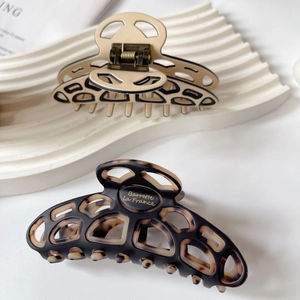 Detail of French acetate hair claws in beige and tortoiseshell with hollow geometric design