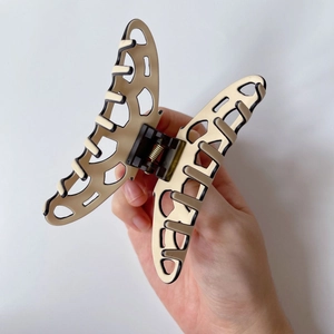 Detail of butterfly hair claw clip with black and cream contrast trim and hollow design