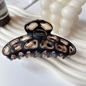 Macro detail of tortoiseshell acetate hair claw clip with geometric cutout on display