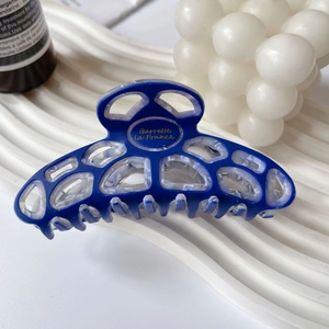 Detail of navy blue hollow geometric acetate hair claw clip with golden lettering