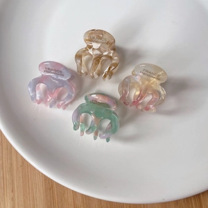 Set of four premium tortoiseshell acetate mini hair claws with marble texture in a ceramic dish