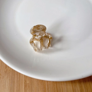 Close-up of a mini acetate hair claw with brown marble texture and France Handmade gold logo