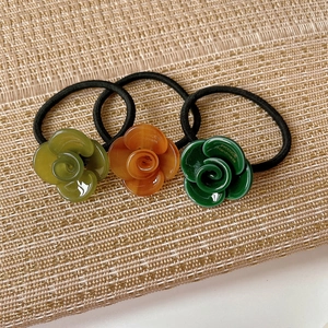 Three-piece acetate camellia floral hair ties in olive, amber, and forest green colors