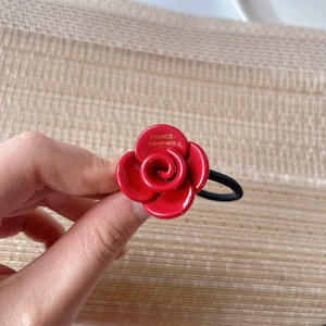 Close-up of a handmade red resin rose hair tie featuring a golden France logo