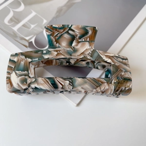 Detail view of acetate marble hair claw with gold France handmade logo engraving