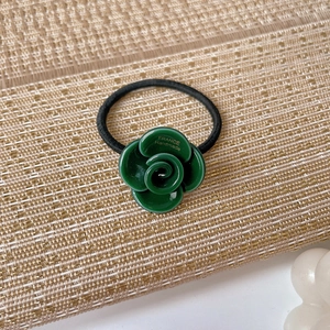 Detail of green acetate camellia flower hair tie with gold France Handmade lettering