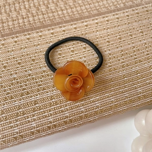 Detail of amber acetate camellia flower hair tie with high elastic black rubber band